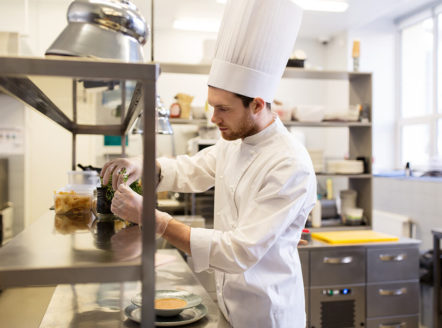 kucharz w kuchni ze stali nierdzewnej